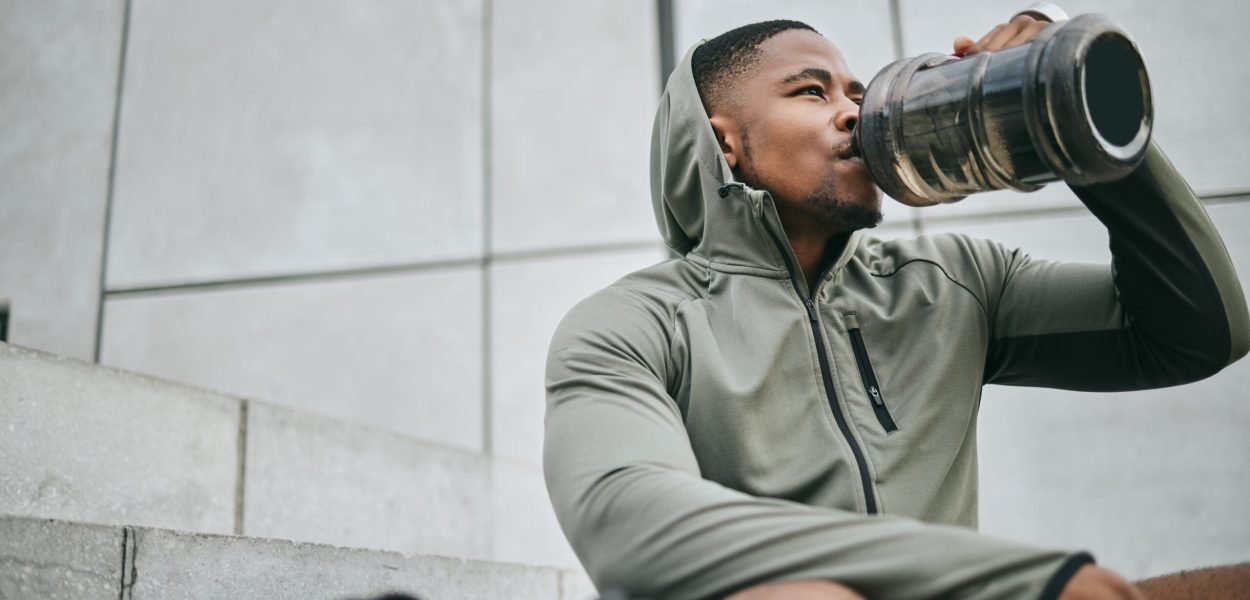Fitness, relax or black man drinking water in training or exercise for body recovery or workout in Chicago, USA. Hydration, thirsty or tired healthy sports athlete drinks natural liquid in bottle.