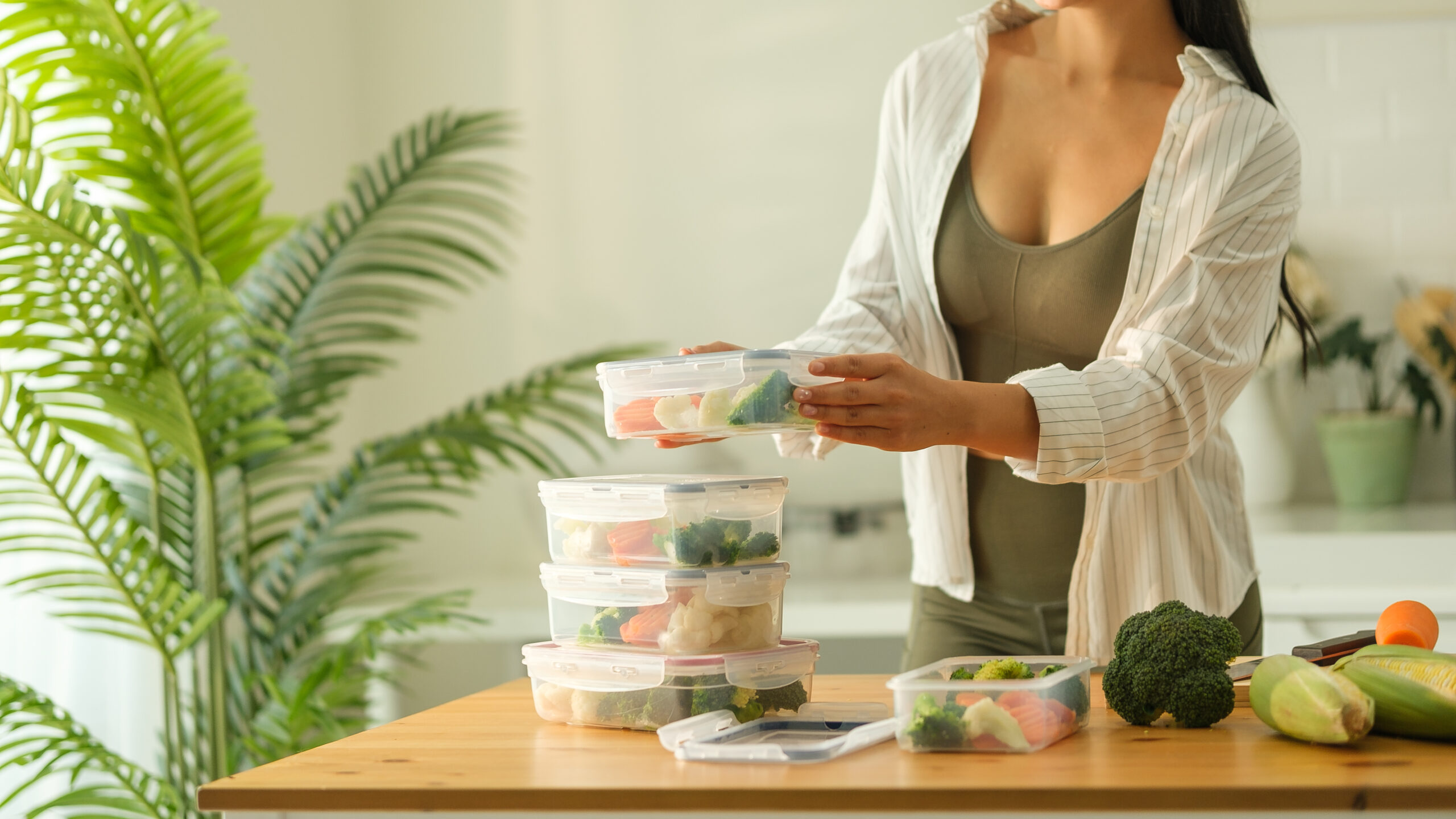 Attractive woman arranging her meal prep containers on the kitchen counter, ready for a week of healthy eating. Healthy lifestyle and nutrition concept.